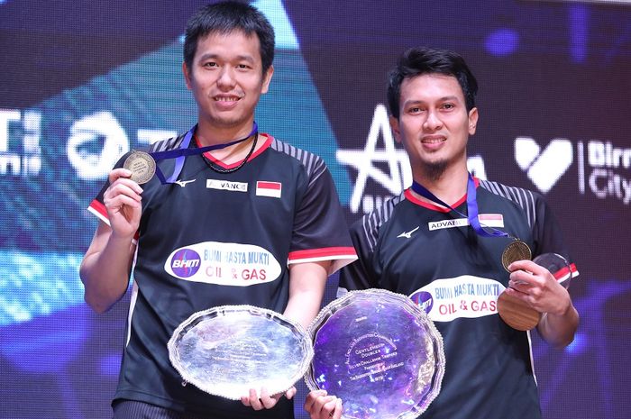 Pasangan ganda putra Indonesia, Mohammad Ahsan/Hendra Setiawan, berpose dengan medali dan trofi juara All England Open 2019 di atas podium kampiun di Arena Birmingham, Birmingham, Inggris, Minggu (10/3/2019).