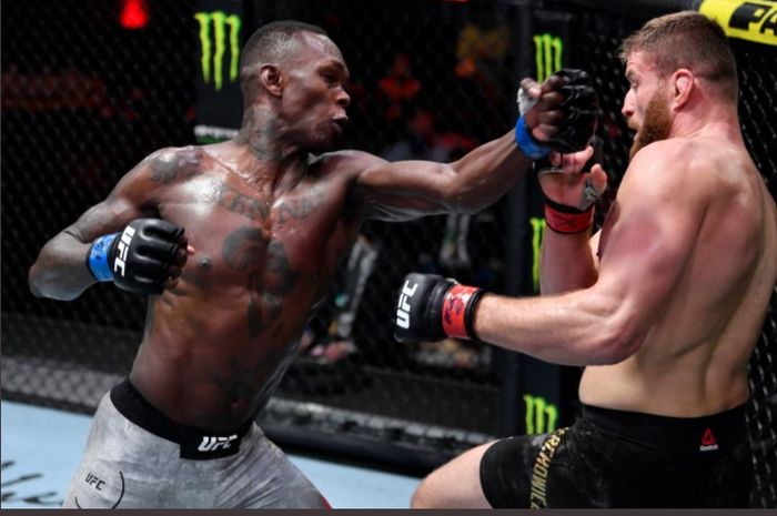 Juara kelas menengah UFC, Israel Adesanya, saat hendak memukul Jan Blachowicz yang terpojok sisi pagar. Kedua petarung saling terlibat bentrok pada ajang UFC 259 di UFC Apex, Las Vegas, Nevada, Amerika Serikat, Minggu (7/3/2021).