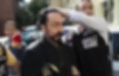 Petugas polisi Turki mengawal televangelis dan pemimpin sekte, Adnan Oktar alias Harun Yahya di Istanbul, saat dia ditangkap atas tuduhan penipuan. Dia terbukti telah melakukan kejahatan seksual yang mengakibatkannya dipenjara lebih dari 1.000 tahun.