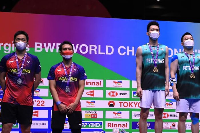 Pasangan ganda putra Indonesia, Hendra Setiawan/Mohammad Ahsan, dan pasangan Malaysia, Soh Wooi Yik/Aaron Chia berpose di podium setelah final Kejuaraan Dunia 2022. Chia/Soh menjadi juara dunia.