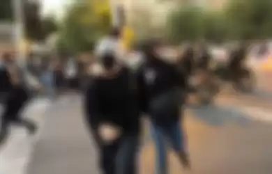 Demonstran Iran berlari dari polisi anti huru-hara di Teheran, Senin (19/9/2022). Demonstrasi rusuh berlangsung di berbagai kota Iran pada pekan ini, memprotes kematian Mahsa Amini, seorang perempuan yang tewas dalam tahanan pada Jumat (16/9/2022) usai ditangkap polisi moral karena tak memakai hijab