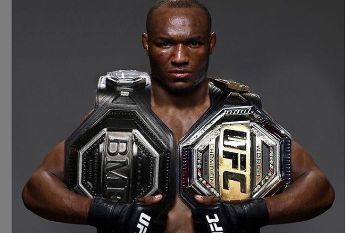 Kamaru Usman berpose dengan titel kelas BMF dan titel kelas welter