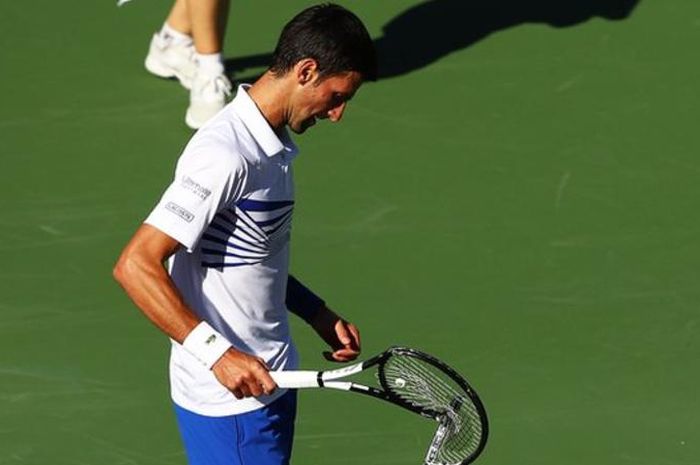 Petenis tunggal putra nomor satu dunia dari Serbia, Novak Djokovic, melihat raketnya yang telah rusak akibat dipukulkan berulang kali ke atas lapangan Indian Wells Masters 2019.