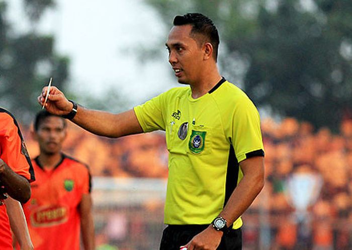 Wasit Pesibo Fariq Hitaba memberikan kartu kuning kepada pemain Madura United, Engelbert Sani, saat 