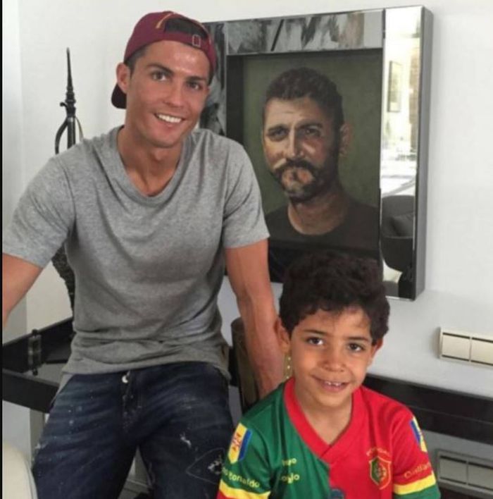 Cristiano Ronaldo dan sang putra, Cristiano Jr. Berdiri di depan foto ayah Ronaldo Jose Dinis Aveiro