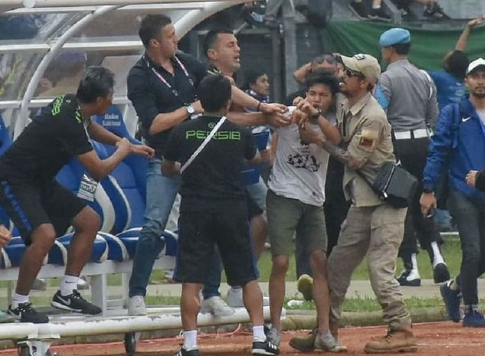 Pelatih Persib Bandung Miljan Radovic (kedua dari kiri) coba melindungi diri saat didatangi seorang suporter yang diduga hendak memukulnya di Stadion Si Jalak Harupat, Kabupaten Bandung, Kamis (7/3/2019) sore WIB, dalam duel Persib versus Persebaya Surabaya di Piala Presiden 2019.