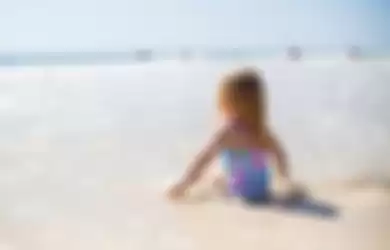Ilustrasi Seorang anak kecil berjemur di pantai.