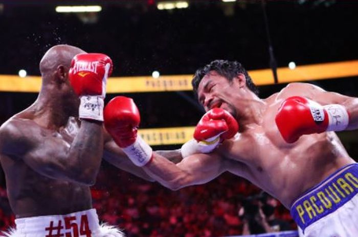 Yordenis Ugas (kiri) saat menerima pukulan dari Manny Pacquiao (kanan) ketika bertarung di T-Mobile Arena, Las Vegas, Nevada, Amerika Serikat, Sabtu (21/8/2021).